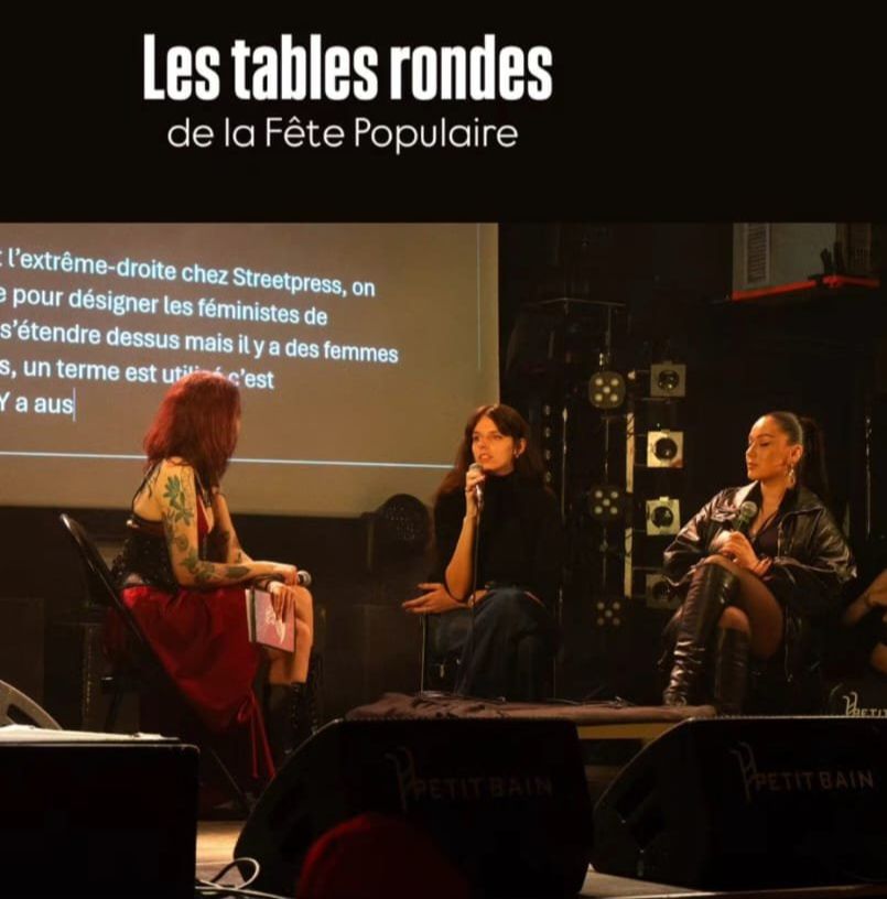 Trois jeunes femmes sur une scène, derrière elles un écran de sous-titrage