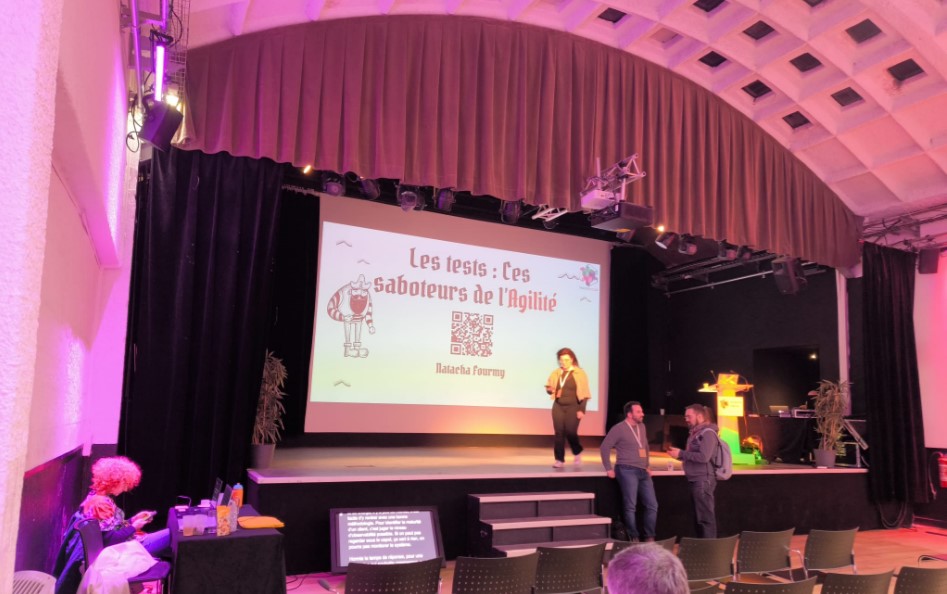 Dans une grande salle de conférences, un petit écran retransmet le sous-titrage