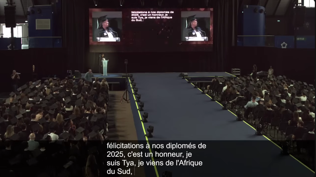 Une diplomée parle devant une salle comble, son intervention est sous-titrée