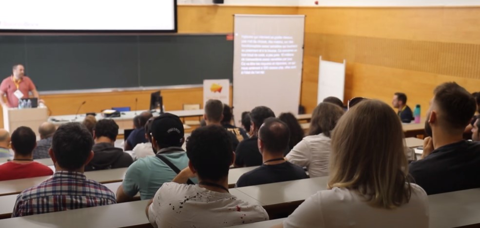 Dans une salle bondée, un grand écran de sous-titrage est installé
