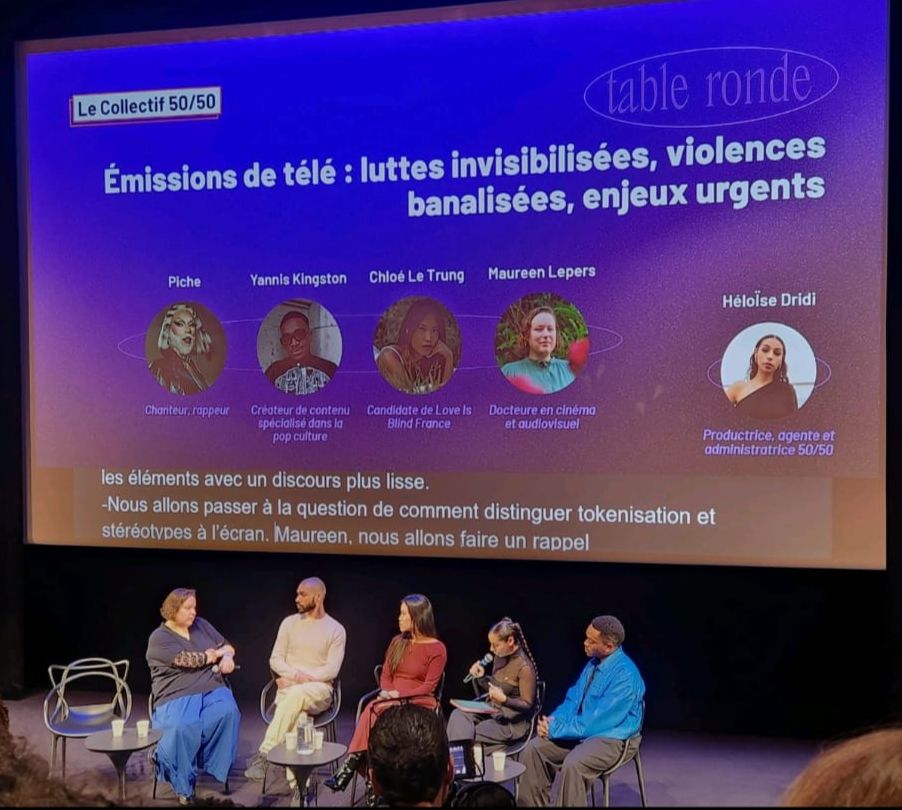 Table ronde avec cinq participants. Sur l'écran s'affiche du sous-titrage en direct.